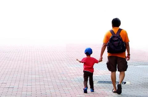 Father and son walking while holding hands Stock Photos