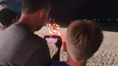 A father and son watching a fire show on the beach. Stock Footage 317812845