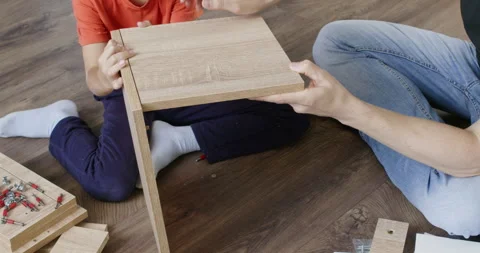 Father and son work together on floor to assemble nightstand Stockbeeldmateriaal 286046569