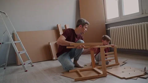 Father and son work together indoors, assembling furniture Stock Footage 297308671