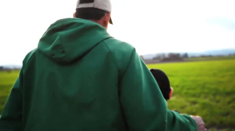 A father and son working on a farm, walk into the sunset Stock Footage