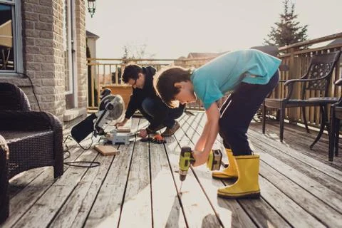 Father and son working on fixing a deck with power tools together. Stock Photos
