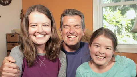 Father and two daughters talking to family on a computer or other device. Stock Footage 129273446