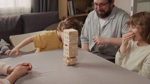 Father and Two Sons Playing Wooden Block Stacking Game at Home Stock Footage 340346421