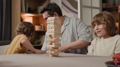 Father and Two Sons Playing Wooden Block Tower Game at Home Stock Footage 340346464