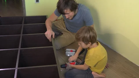 Father and young son build a large bookshelf together using an electric Video stock 325207052