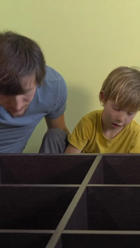Father and young son build a bookshelf together using an electric screwdriver Video stock 332563792