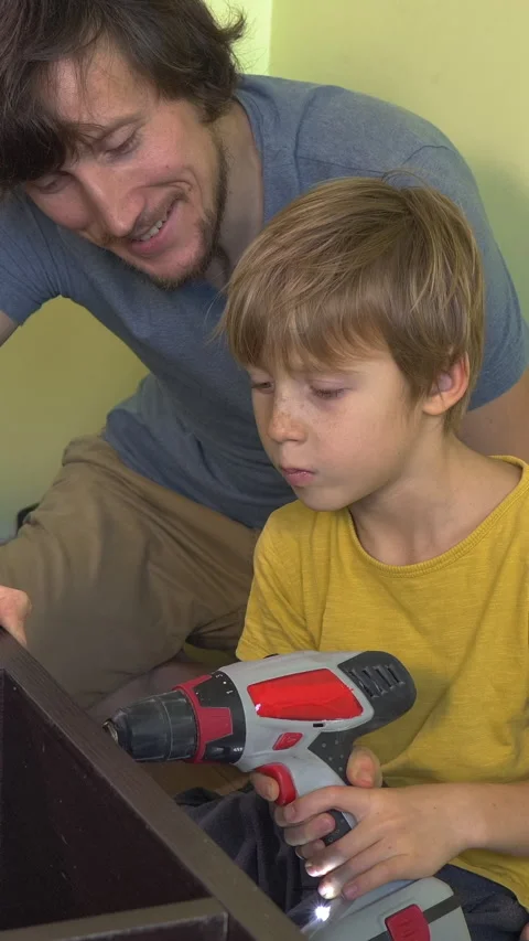 Father and young son build a bookshelf together using an electric screwdriver Video stock 332563819
