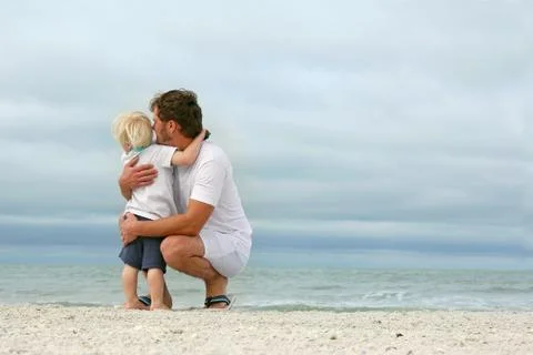 Father and young son looking out over ocean Stock Photos