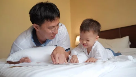 Father andAsian 2 years old toddler baby boy child reading bedtime story book  Stock Footage