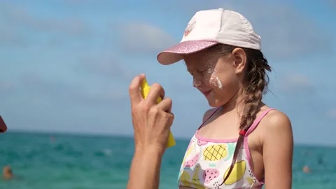 Father applying protective cream to her daughter's face at the beach. Stock Footage 160310331