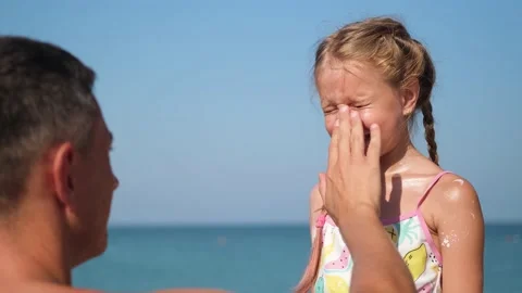 Father applying protective cream to her daughter's face at the beach. Stock Footage 173515537