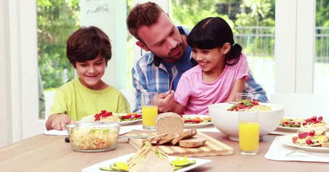 Father assisting children while eating lunch Stock Footage