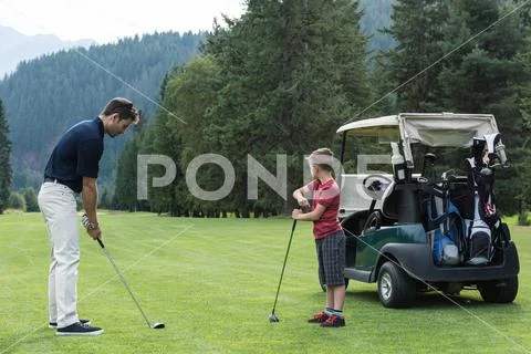 Father Assisting His Son To Play Golf