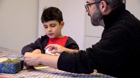 Father assisting son with present decoration Stock-Footage 345253392