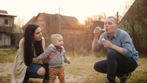 Father blowing soap bubbles for his baby son Stock Footage 127983885