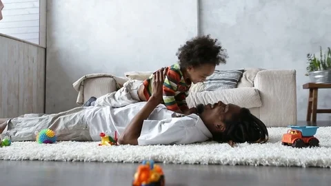 Father bonding with toddler son lying on carpet Stock Footage