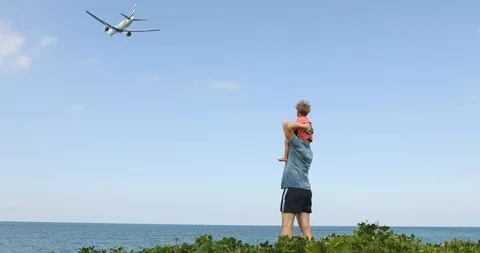 Father with boy on shoulders looking at flying plane Stock Footage 101359805