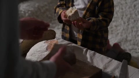 Father breaks bread piece and offers it to daughter, hands and bread close-up. 库存影片 309259345
