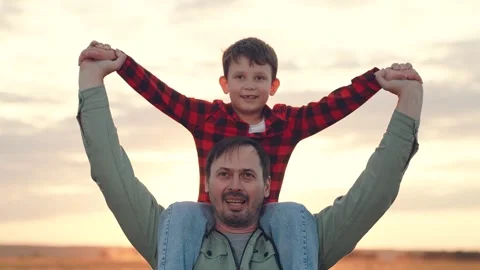 Father carries son on shoulders at back sunset on family vacation in countryside Stock Footage 255862552