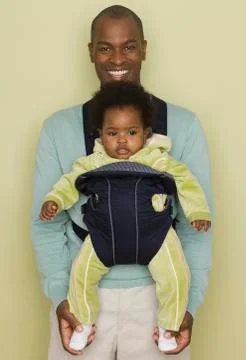 Father carrying baby daughter in carrier Stock Photos