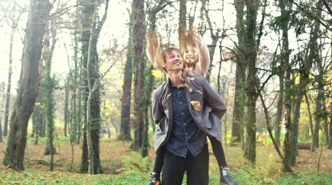 Father carrying daughter on back and she is throwing leaves in the air Stock Footage 59553919