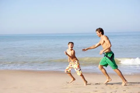 Father chasing young boy on beach Stock Photos