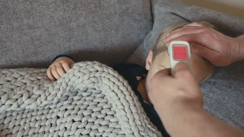 Father checking sons temperature with contactless thermometer 스톡 동영상 347099575