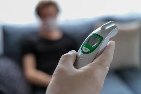 The father is checking temperature his son's with infrared thermometer at the Stock Photos
