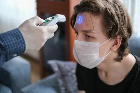 The father is checking temperature his son's with infrared thermometer at the Stock Photos