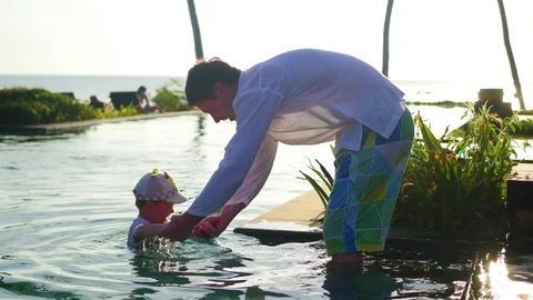 Father with a child playing in the pool next to the beach, sunset time. Tropical Video stock 76090282