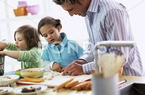 Father with children (4-7) preparing meal Stock Photos