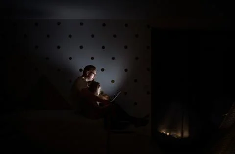 Father with children sitting indoors in bedroom, using laptop. Stock Photos