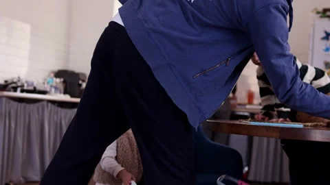 Father clearing table near two children while mother works in kitchen Video stock 330042887