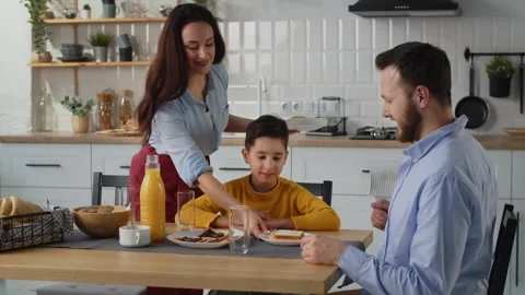 A father communicates with his son during breakfast in the kitchen. A brunette Video stock 240195706