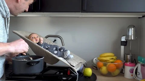 Father cooking while he puts his baby on a sink 스톡 동영상 122274645