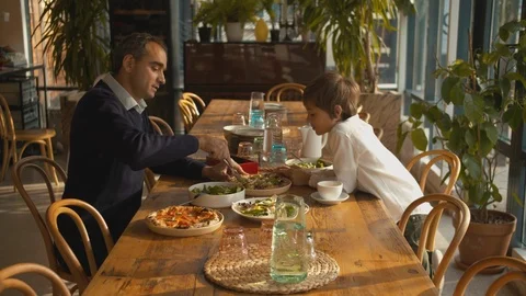 Father cuts pizza at lunch with son Stock Footage 120794512