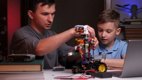Father dad explains to son how to build and set up a robot Stock Footage 238678525