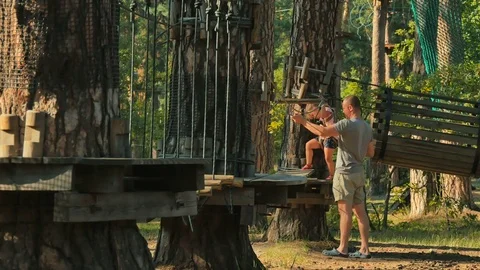 Father with daughter spends their weekends in rope park Stock Footage