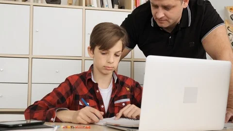 Father dictates to son the correct answer to the question from hometask close up Stock Footage 111334128