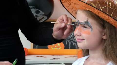 Father drawing aqua makeup on kid girl face for Halloween party Stock Footage 219462029