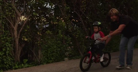 Father encourages son learning to ride bike, dad teaching bicycle riding to kid Stock Footage