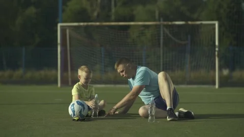 Father explaining soccer formation to his young son while sitting on field. Video stock 245578869