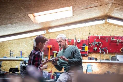 Father explaining tool to son in auto repair shop Stock Photos