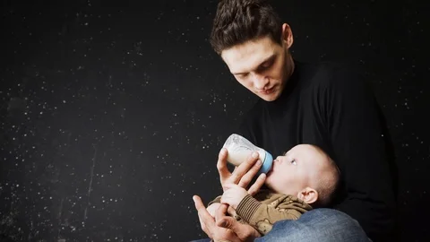 Father feeds the baby. The son eats from the bottle in his father's hands Stock Footage 88828064