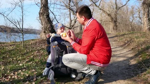 Father feeds the kid with a spoon while walking outdoors Stock Footage 149111840