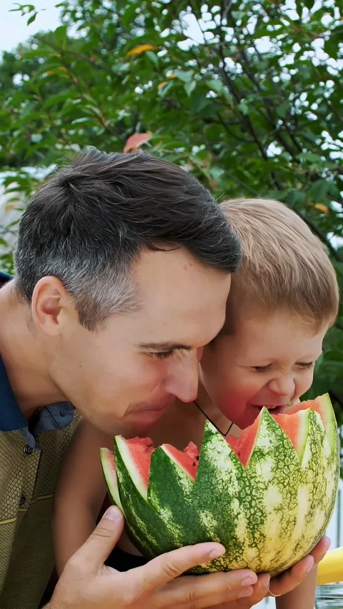 Father with a four-year-old son cut a watermelon and eat it, have fun, a boy Stock Footage 313230663