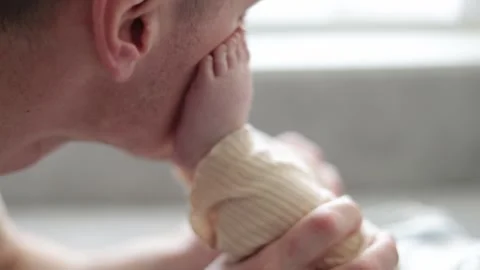 Father gently kisses baby's tiny foot in a tender moment of love and connection Stock Footage 340586866