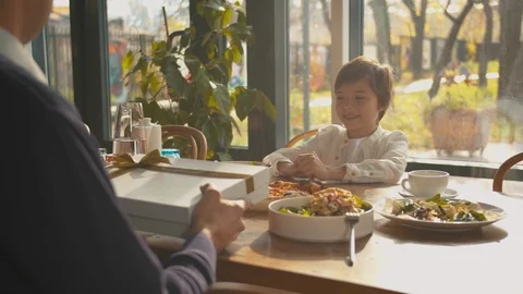 Father gives a present to his son at lunch Stock Footage 120795067