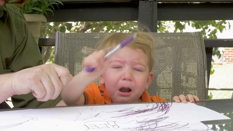 A father hands a marker to his crying frustrated young child boy in slow motion Stock Footage 75658298